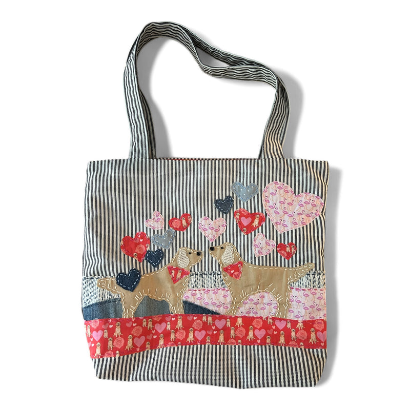 The Pupperfish 2 goldens kissing with hearts floating around, hand stitched design on a striped fabric tote bag